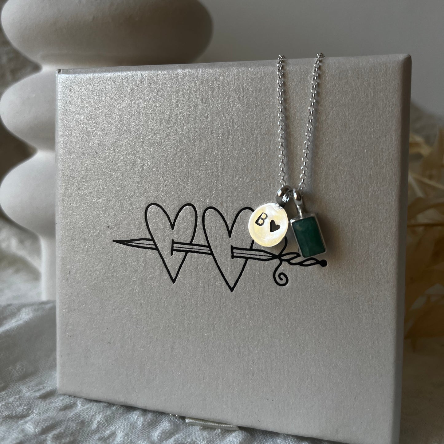 Rectangular pendant with green stone and round medal with initial and a small heart design made of sterling silver