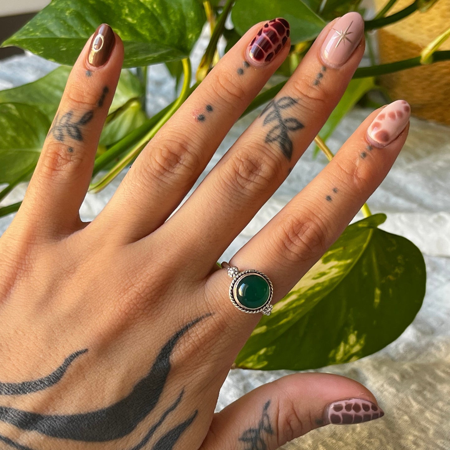 Sterling silver ornamental ring with round green stone in the middle and flowers attachments on the side