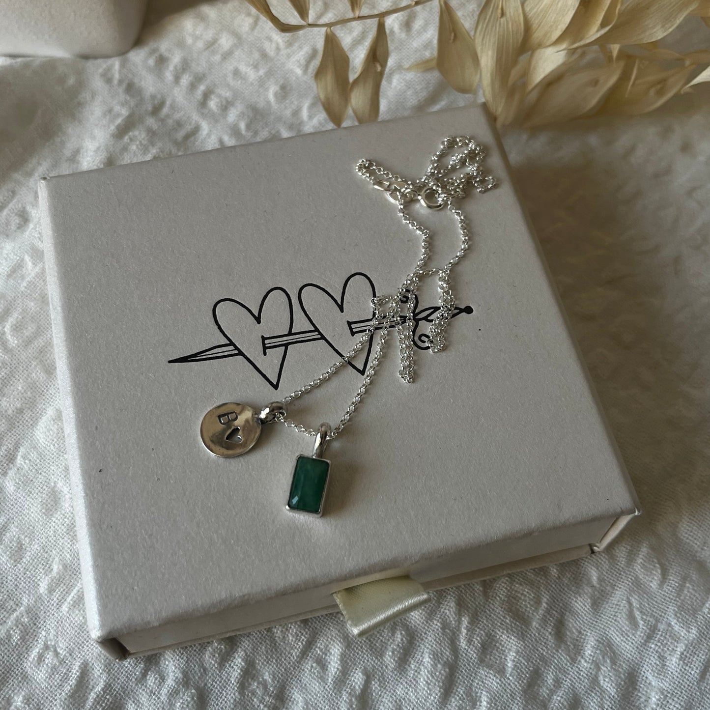 Rectangular pendant with green stone and round medal with initial and a small heart design made of sterling silver