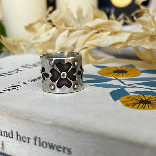 Chunky handmade silver ring with an ornamental flower design in the center, crafted in sterling silver with darkened details.