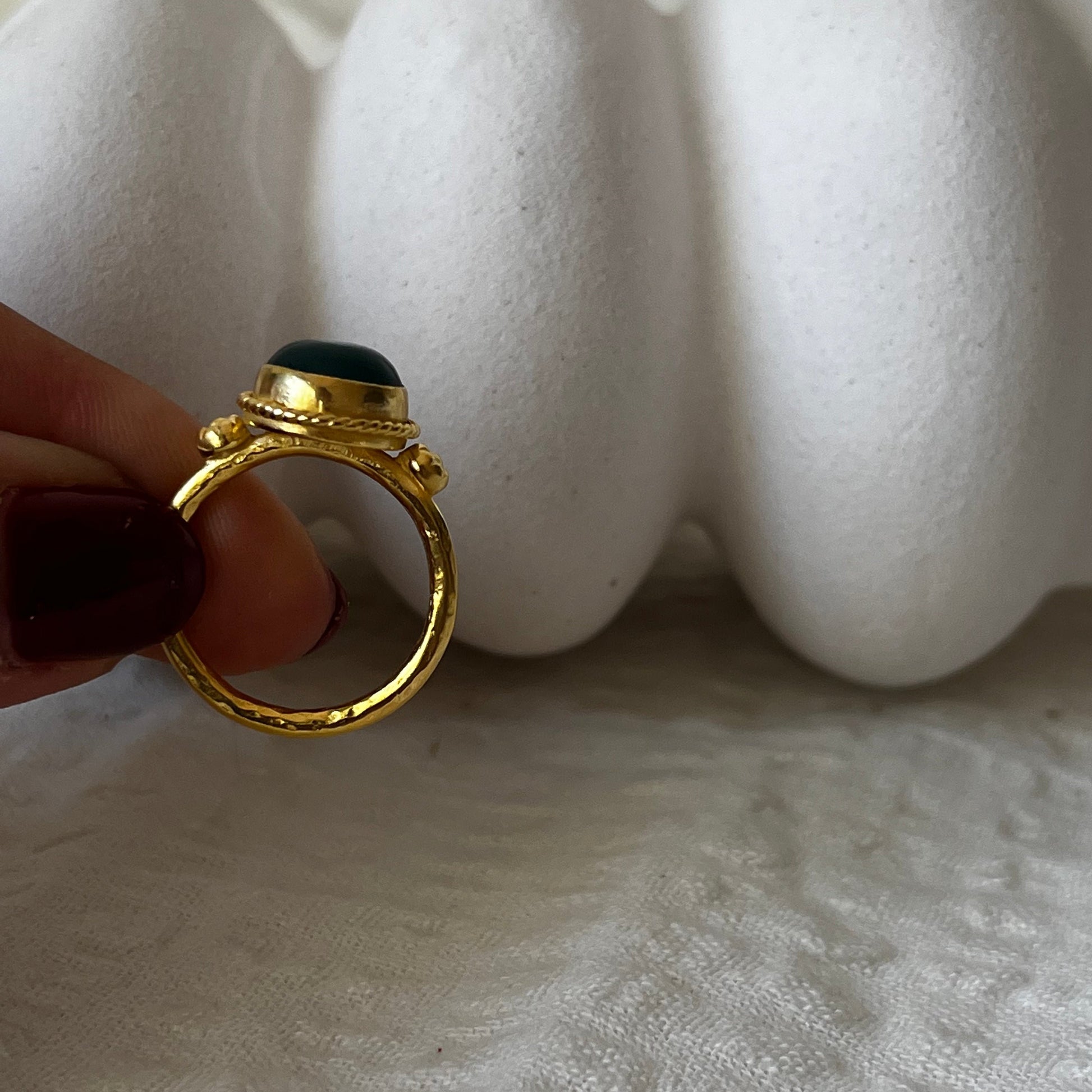 Gold plated ornamental ring with round green stone in the middle and flowers attachments on the side