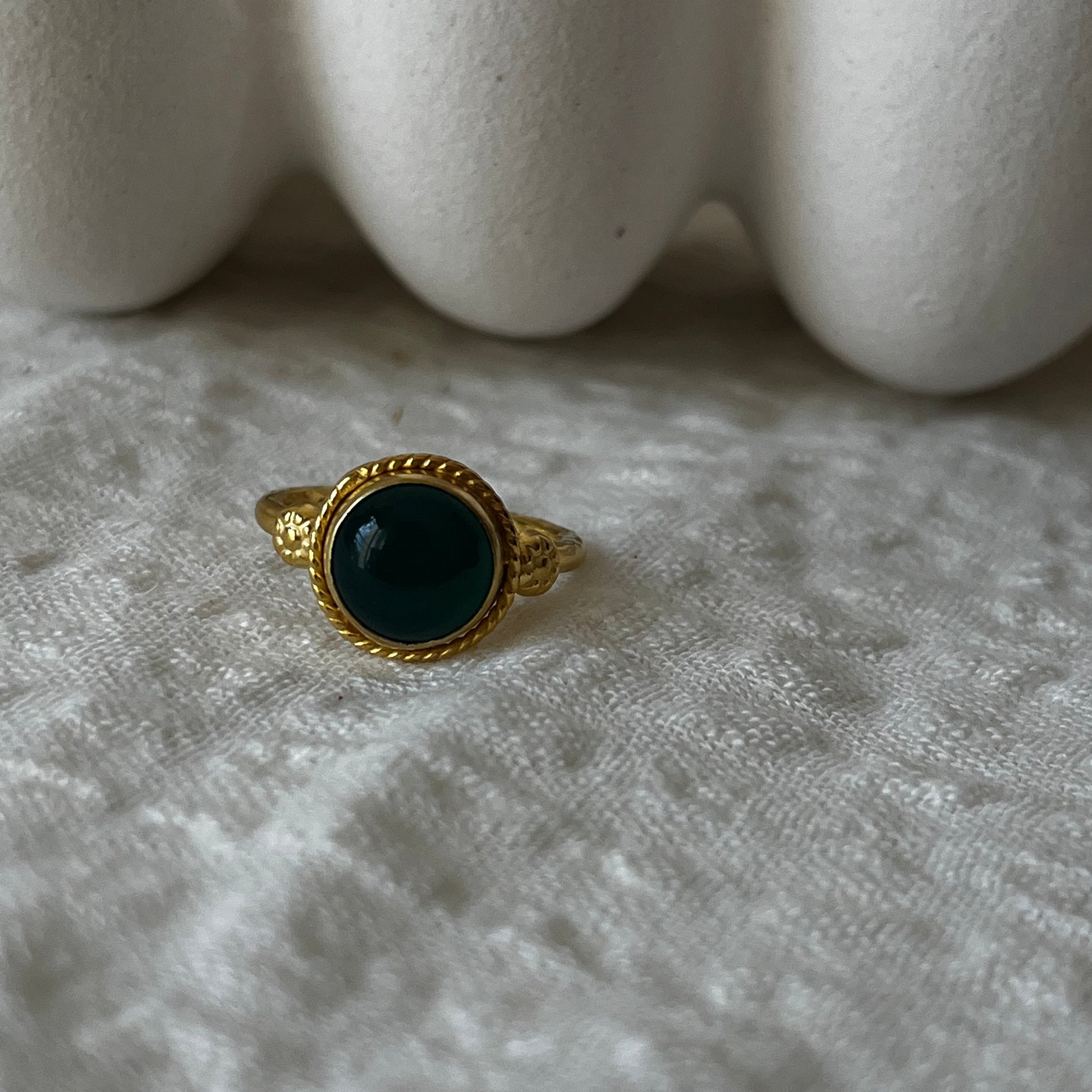 Gold plated ornamental ring with round green stone in the middle and flowers attachments on the side